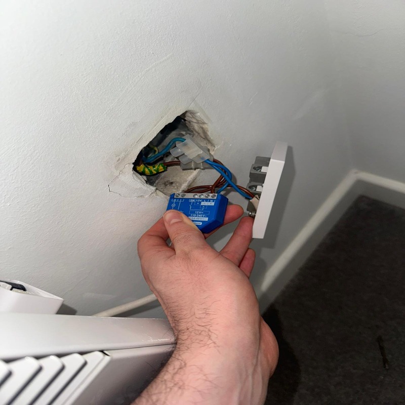 BuildSpark electrician London inspecting a blue smart relay in a wall during fault finding for no power to a radiator.