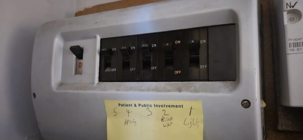 Old consumer unit (fuse board) before upgrade in Tooting, South West London. BuildSpark electrician inspecting an outdated fuse board prior to installing a modern 18th Edition consumer unit with RCBO and surge protection.